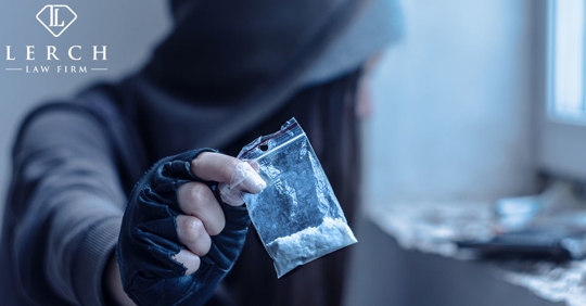woman with hood up holding a small bag of cocaine in a dim room